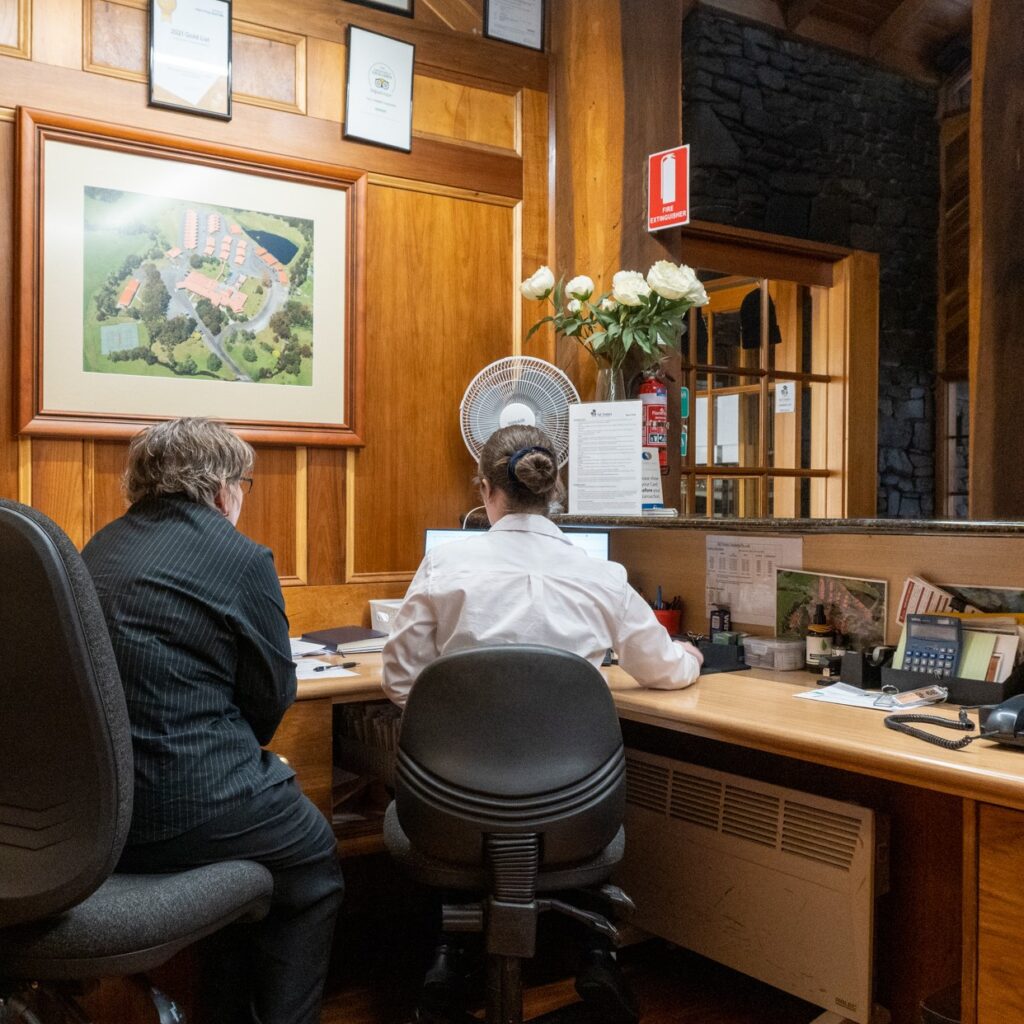 Two people sitting at reception computer working together