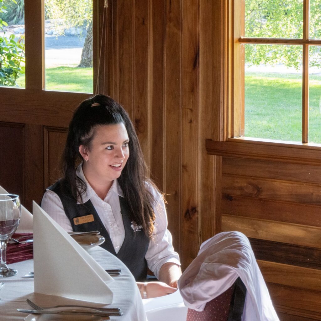 Staff member smiling to someone out of shot while putting covers on chairs