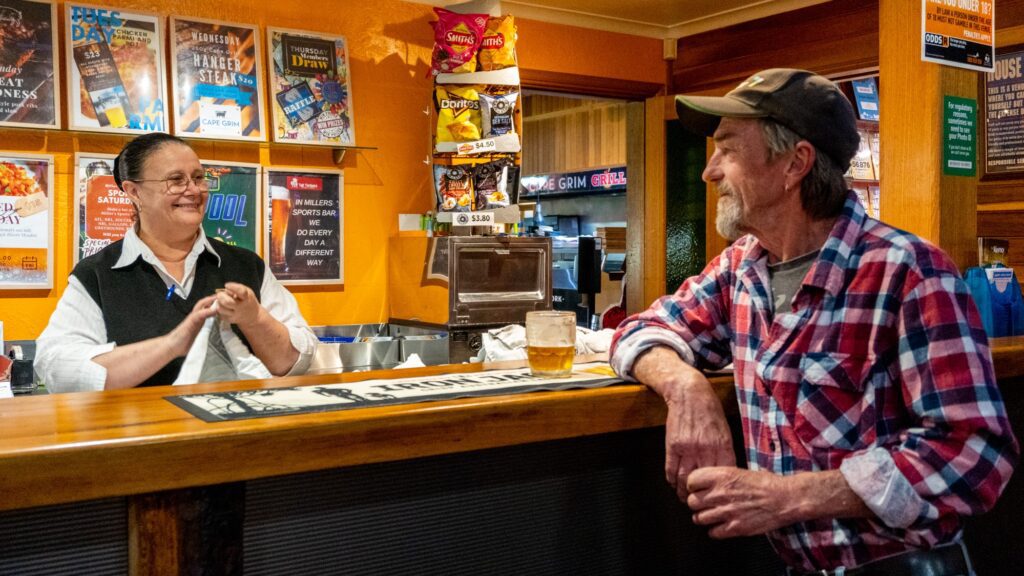 Kim talking with local gentleman while folding towels in Millers Sports Bar