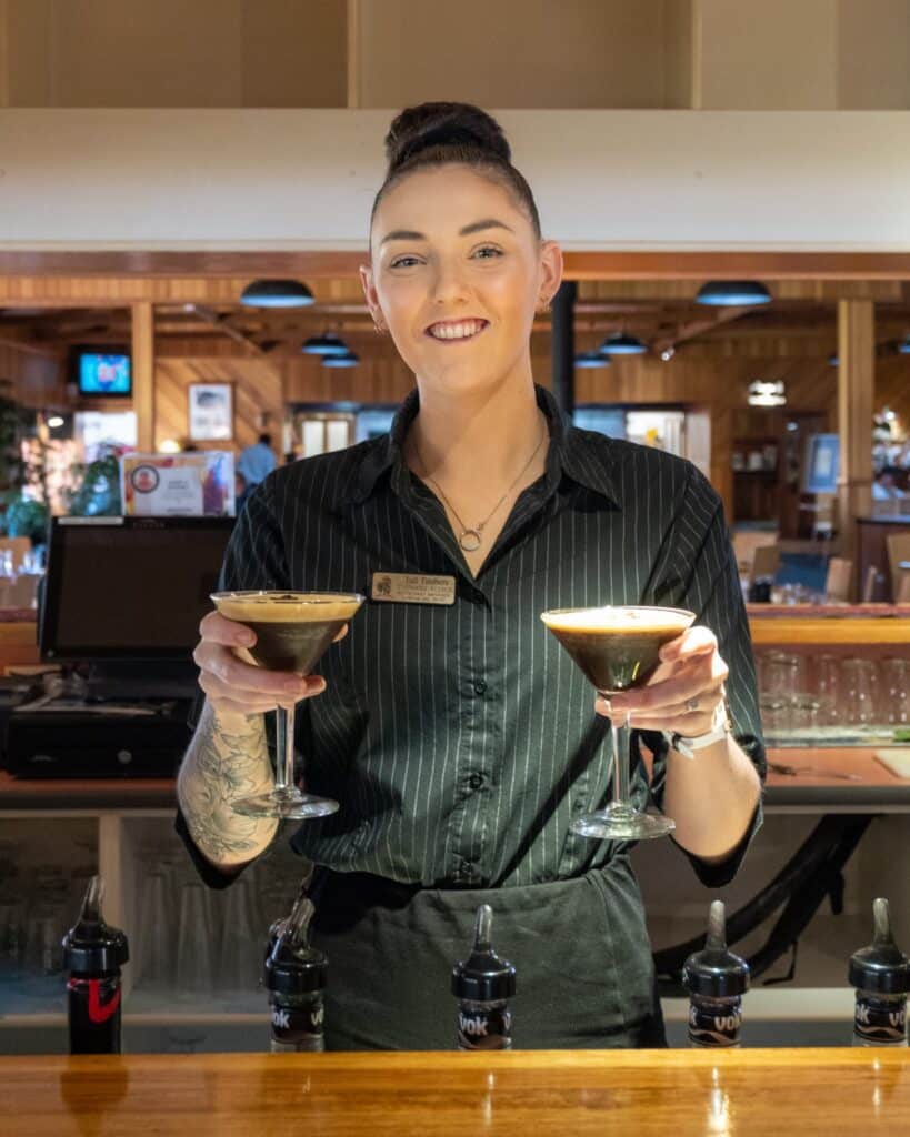 Steph holding two espresso martinis and smiling