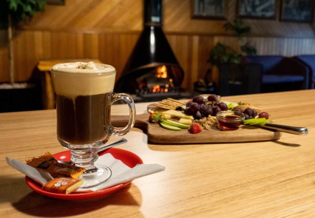 Coffee liqueur and cheese platter on table with fire in background