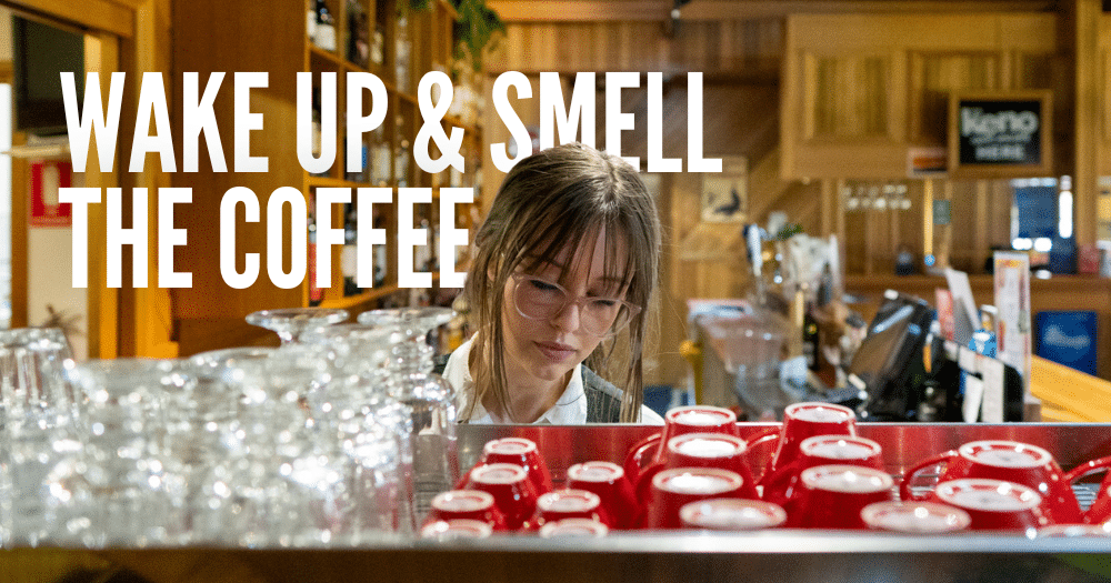 'Wake up & smell the coffee' text overlayed on image of Aysha making coffee with rows of glasses and mugs in foreground