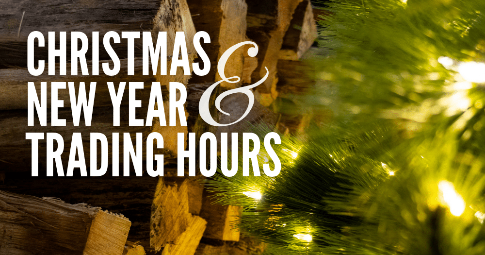 'Christmas & New Year Trading Hours' text overlayed on image of stacked fire wood in background, with lit Christmas tree in foreground