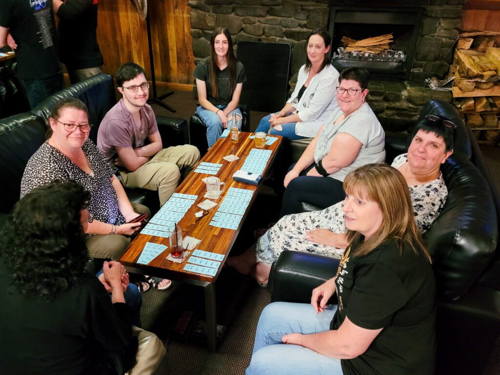 A group of locals including staff sitting around table with raffle tickets all laid out