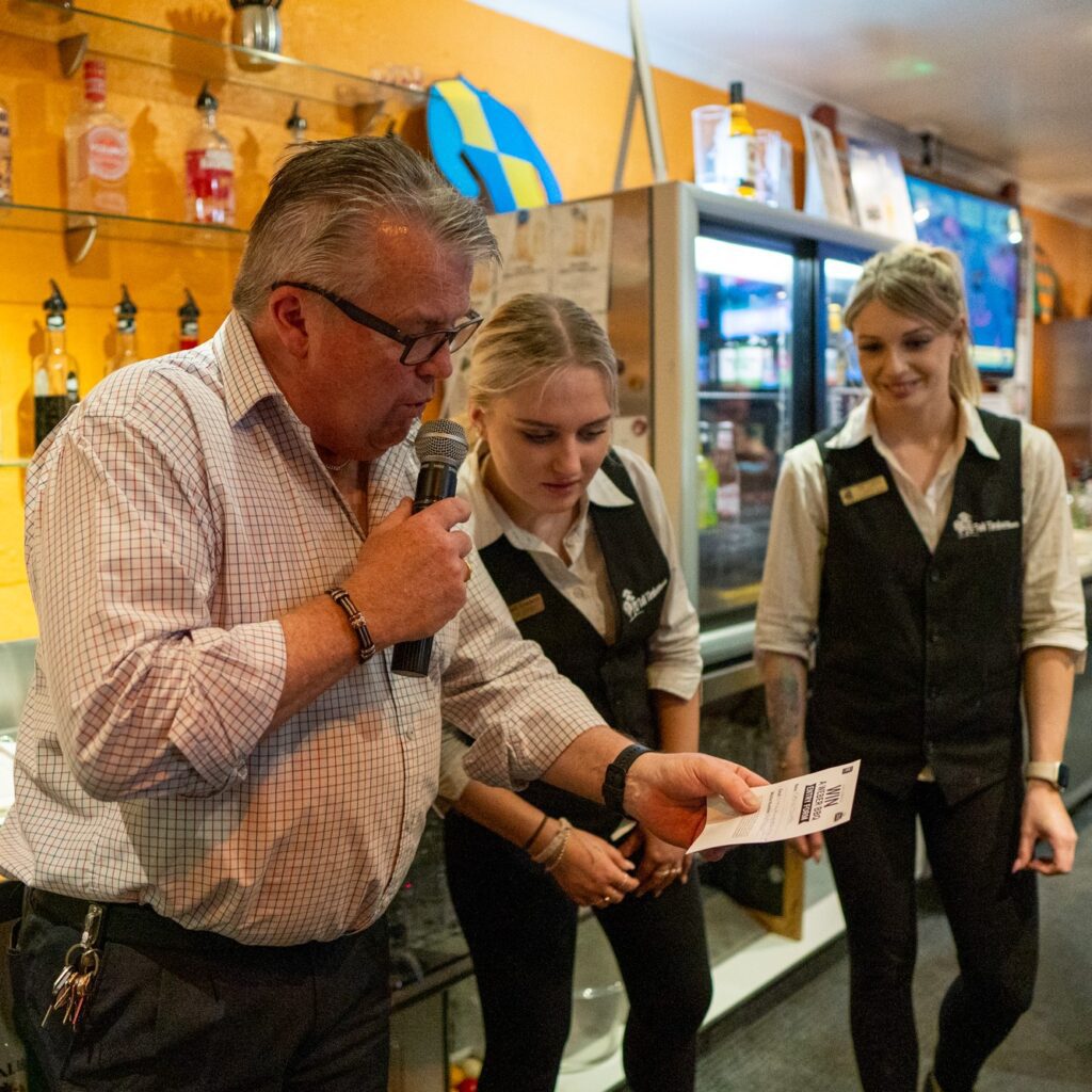 John Dabner calling out winners name with Rylee and Leah looking on