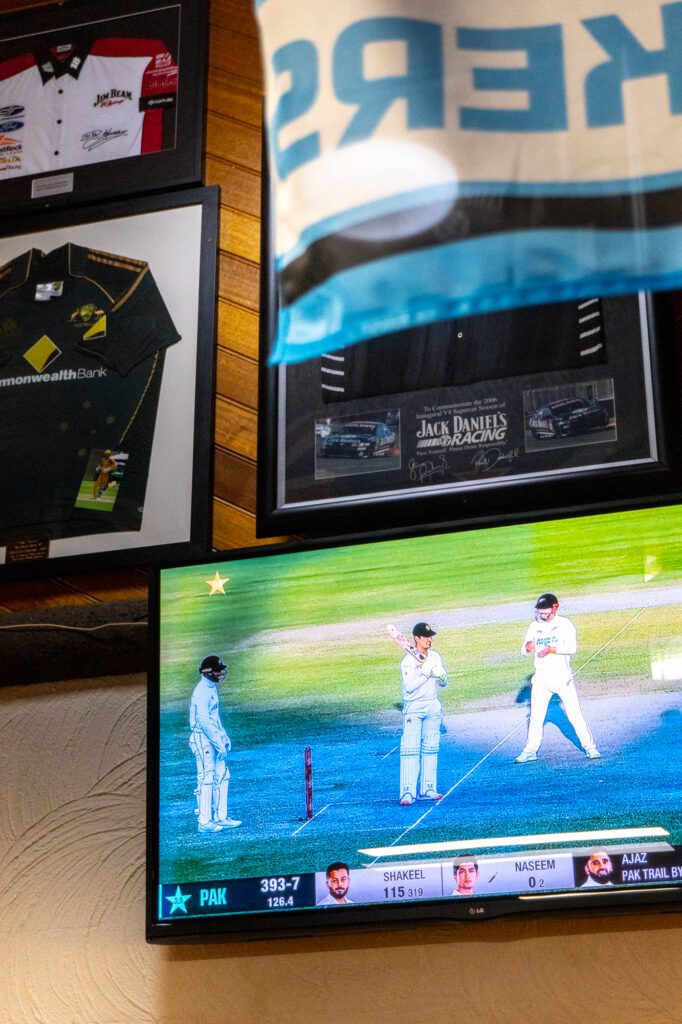 Cricket playing on TV with sport memorabilia on the wall