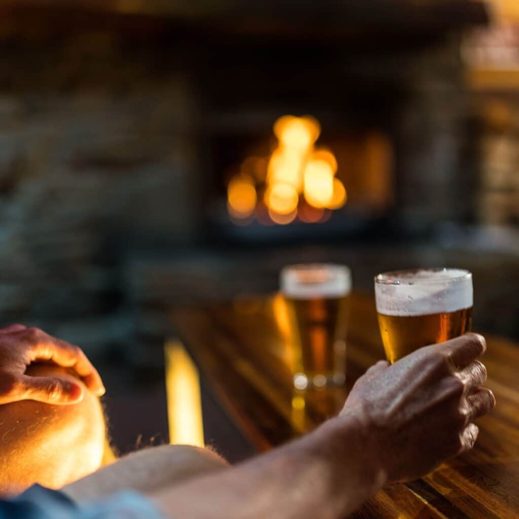 Man holding beer in front of fire place in Millers Sports Bar