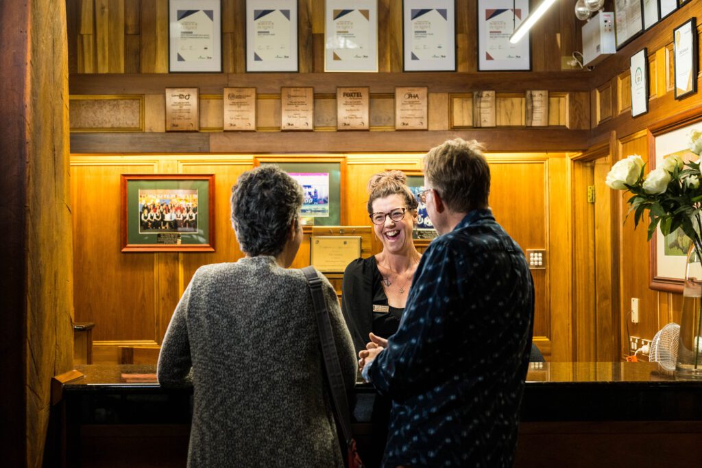 Woman with big smile serving a couple checking in at reception